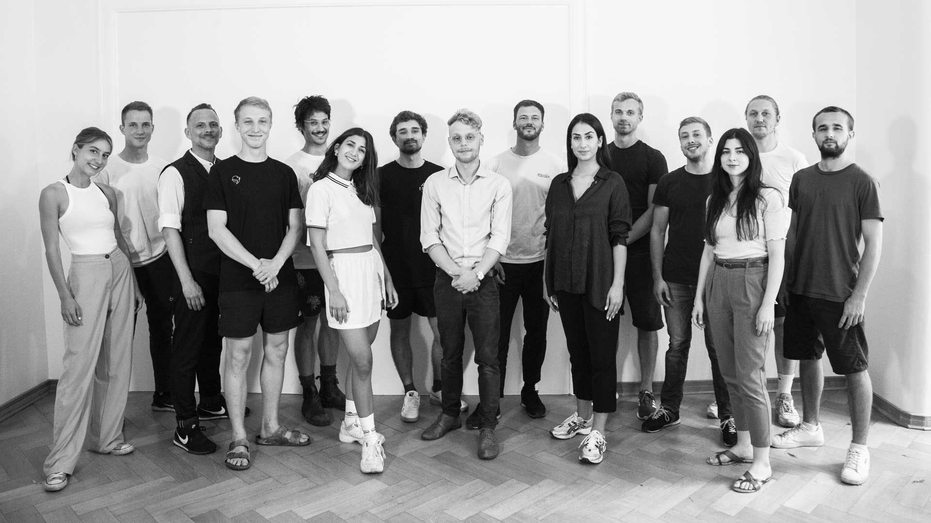 Eine Gruppe von Menschen (Sanaleo Team) posiert gemeinsam in einem schlicht eingerichteten Raum. Dies vermittelt ein freundliches und einladendes Ambiente, passend für ein E-Commerce-Geschäft, das sich auf CBD-Produkte wie Blüten, Öle und Tabakersatz spezialisiert.