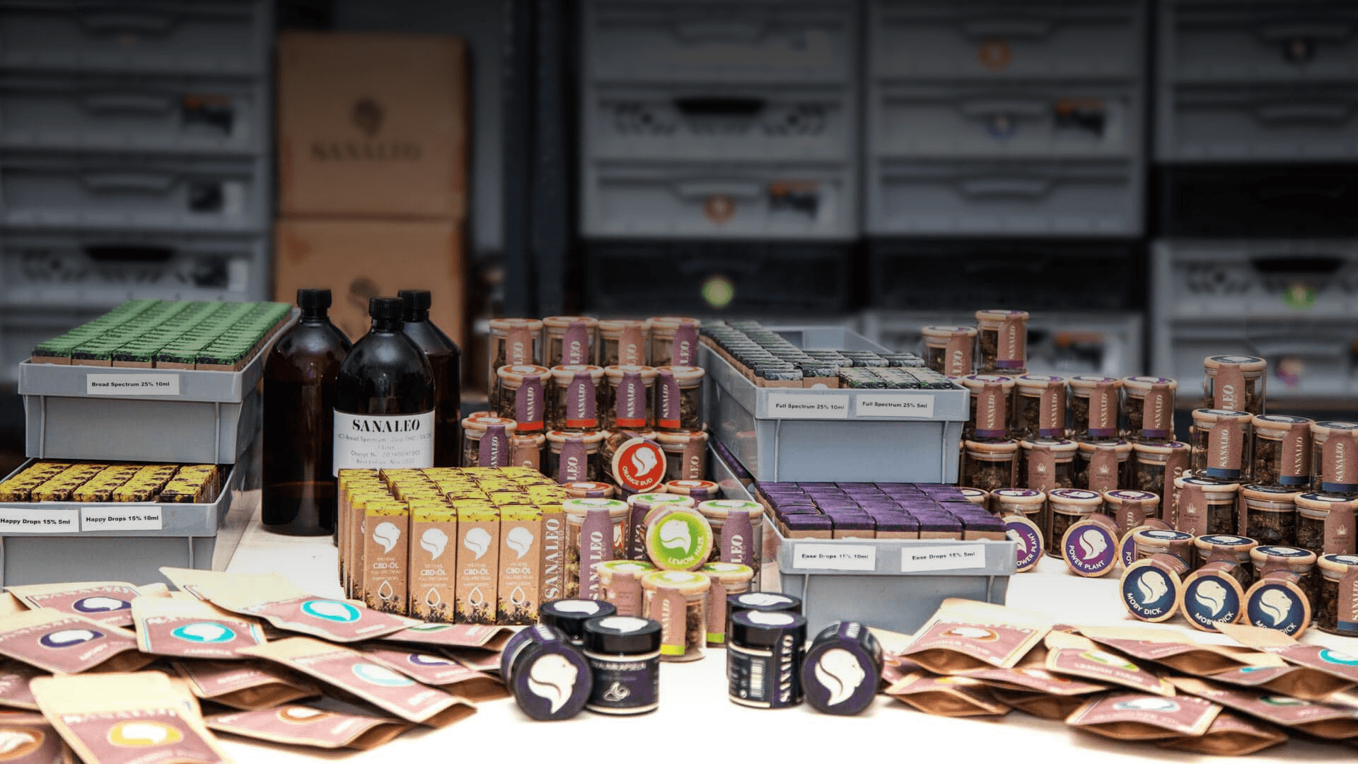 Vielfältige Auswahl an CBD-Produkten, darunter Öle, Blüten und Tabakersatz in verschiedenen Verpackungen, präsentiert auf einem Verkaufstisch. Ideal für Wellness und Entspannung.