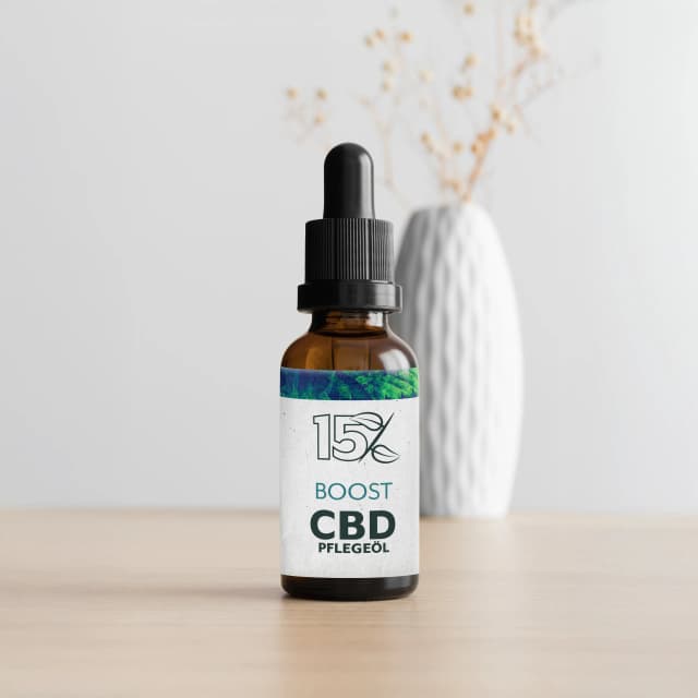 Braune Glasflasche mit 15% BOOST CBD Pflegeöl und Pipette, hochwertiges CBD-Öl für Hautpflege, auf hellem Holztisch vor neutralem Hintergrund.