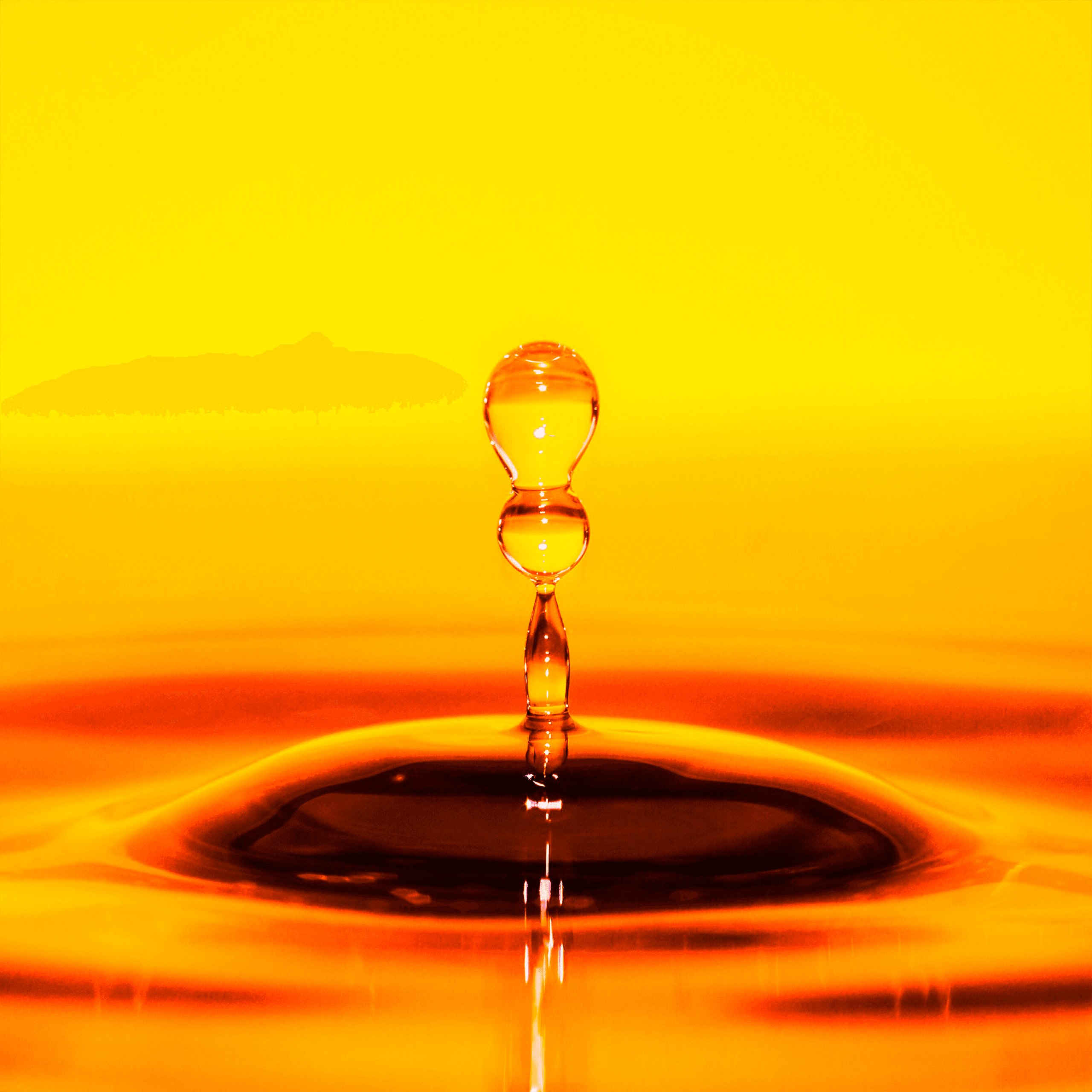 Wassertropfen in dynamischem Sprung vor leuchtend gelbem Hintergrund, symbolisiert Reinheit und Frische von CBD-Ölen.
